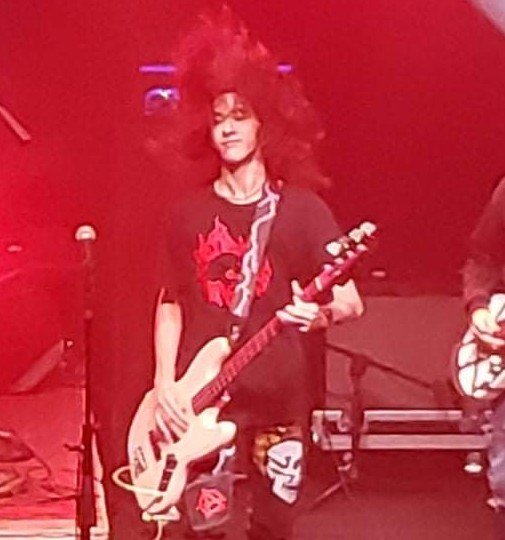 Milo Powers playing bass under red stage lights